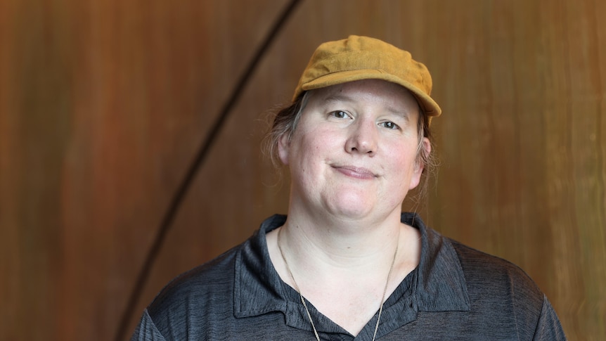 A woman wearing a cap looks at the camera