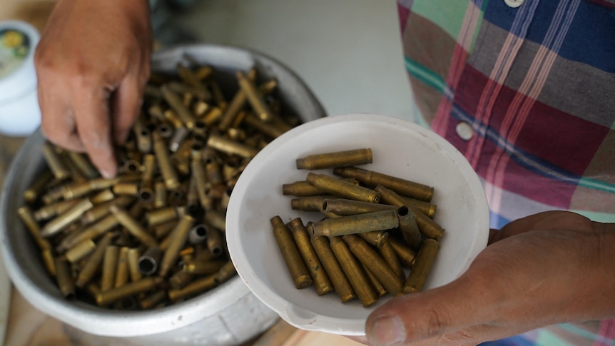 Thoeun Chantha sorts through bowls of bullet casings