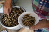 Thoeun Chantha sorts through bowls of bullet casings