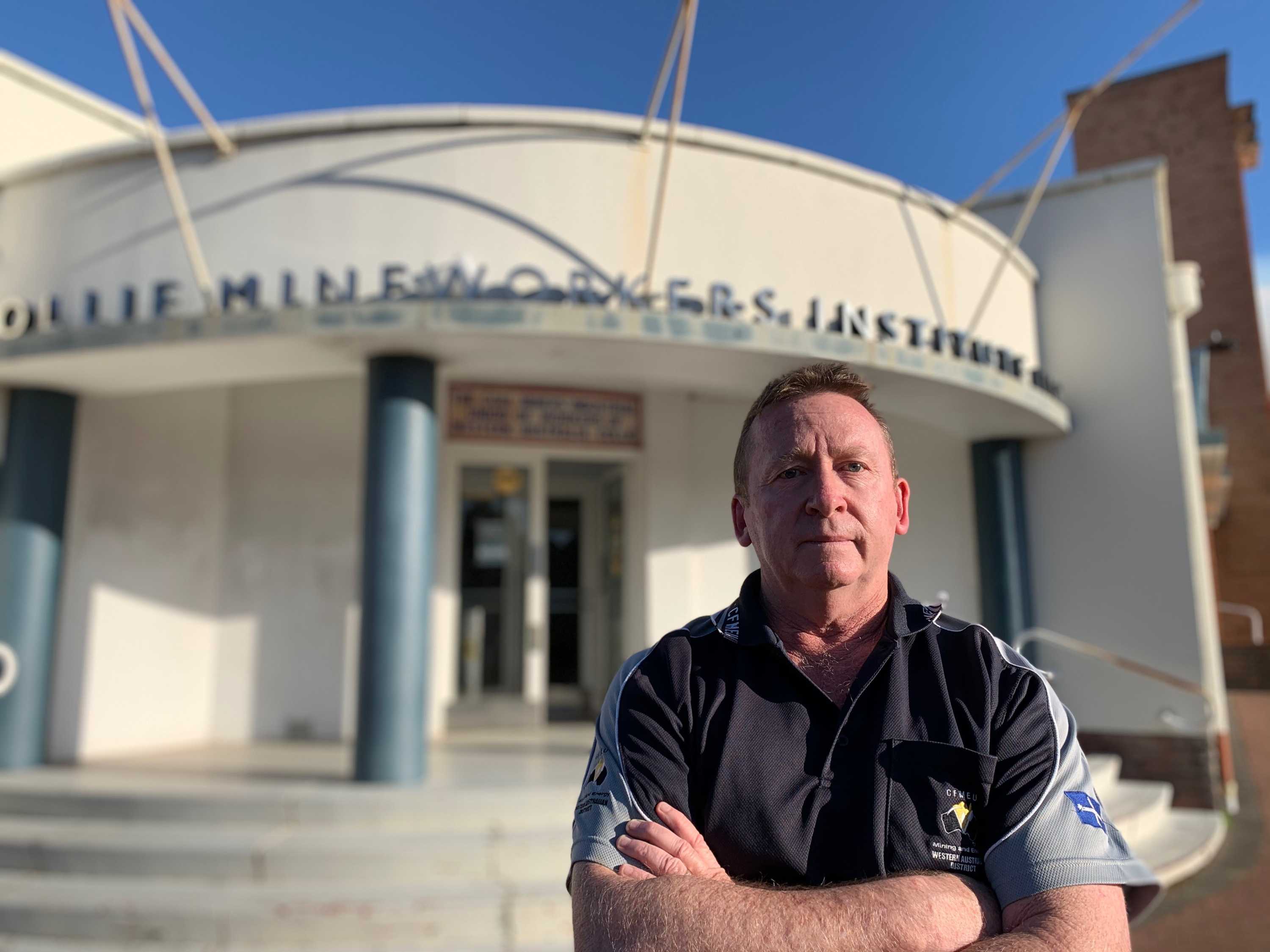 Greg Busson stands with his arms folded outside a building in Collie.