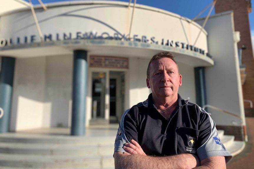 Greg Busson stands with his arms folded outside a building in Collie.