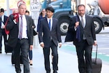 Lloyd Rayney walking along a city street flanked by two lawyers.