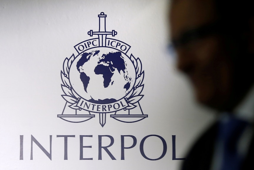 A man passes an Interpol logo