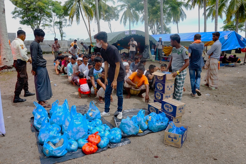 A group of men sitting waiting to food distribution packed in paper and plastic bags
