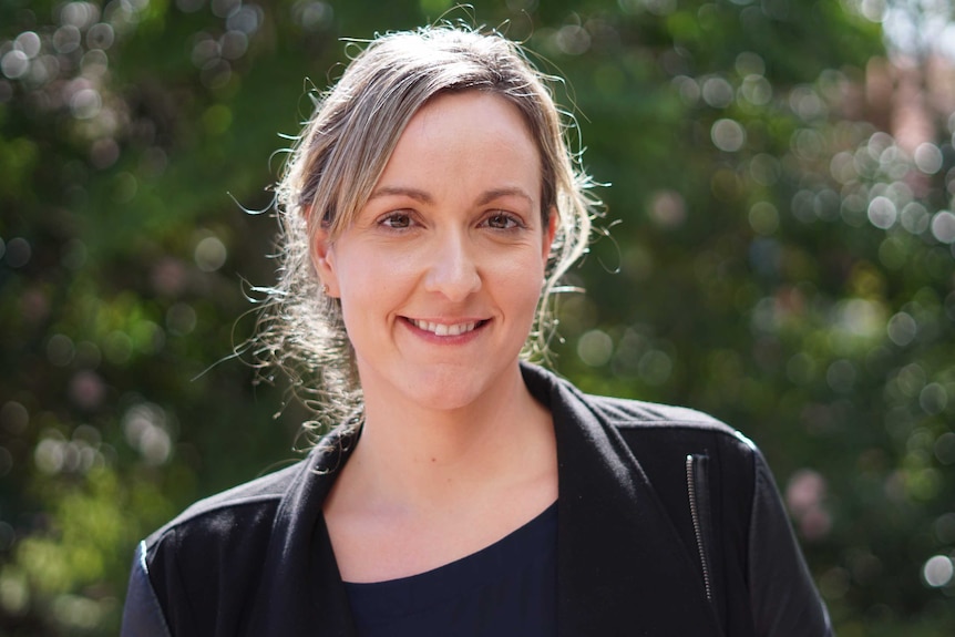 A headshot of a woman in front of foliage.