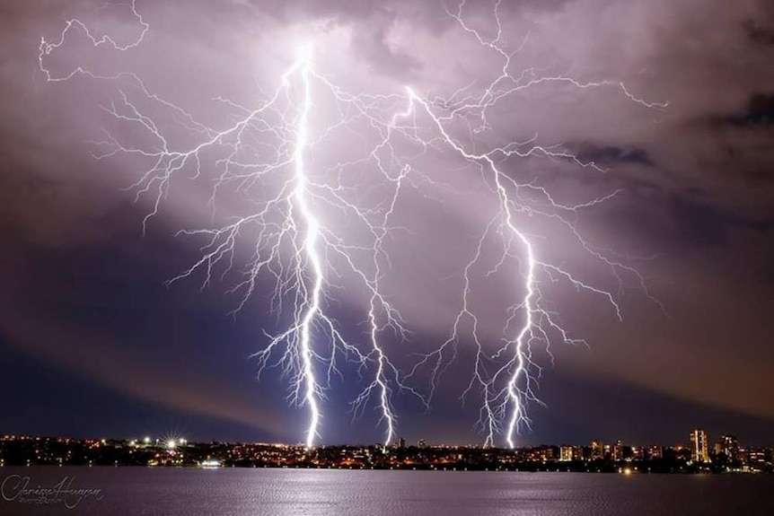 Lightning strikes over the Swan River as a thunderstorm hits Perth.