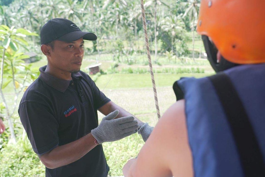 Komang Artawan looks away from the camera as he instructs a tourist on what to do.