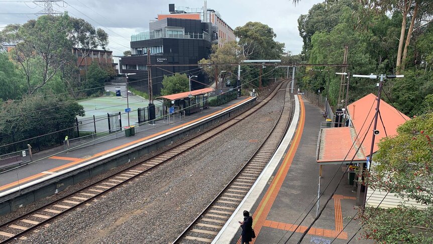 Railway lines run between two platforms next to a college building.