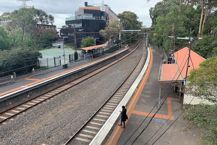 Railway lines run between two platforms next to a college building.