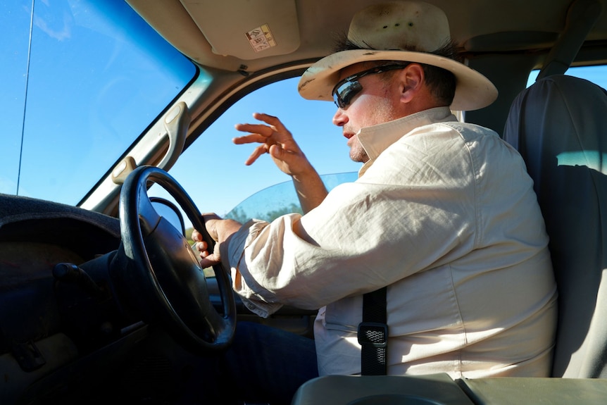 A man gestures with his hand as he drives a vehicle.