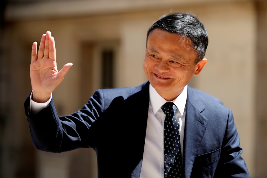 Jack Ma in a suit smiles and waves