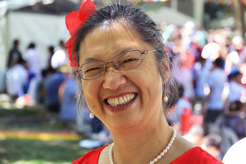 A Chinese woman in a bright red dress, with a red silk flower in her hair.
