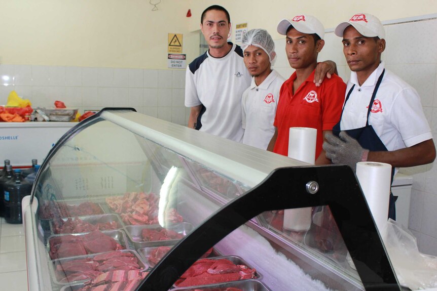Four men stand beside meat in a fridge, butcher shop Dili, East Timor