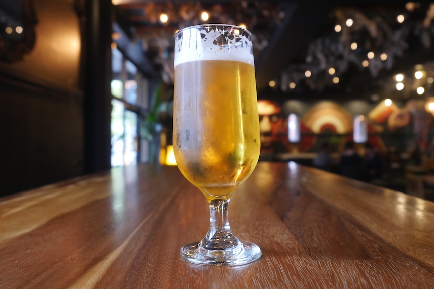 glass of beer sitting on a table in a pub