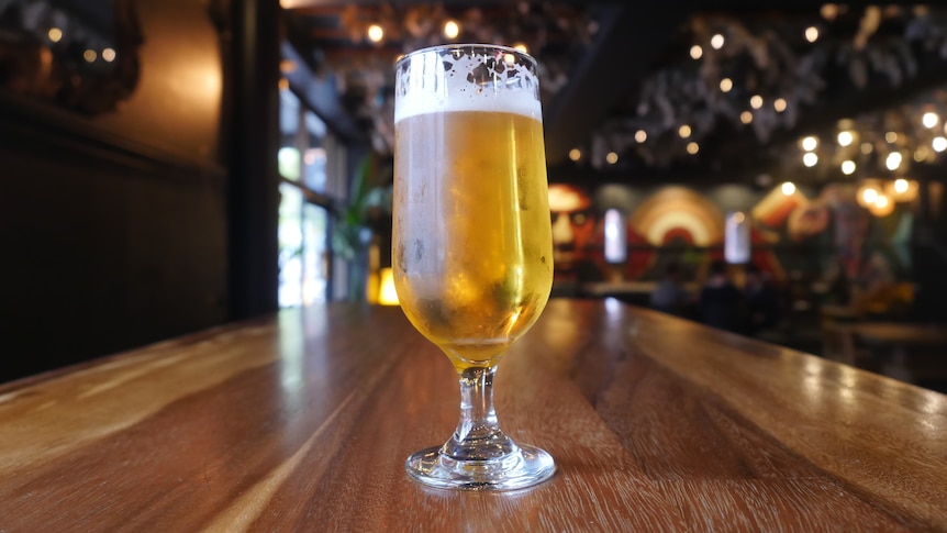 glass of beer sitting on a table in a pub