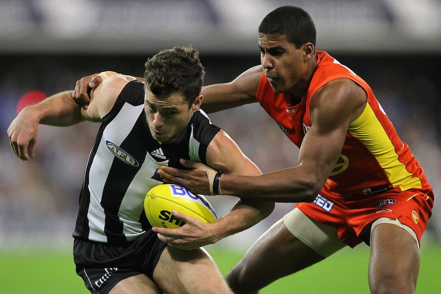 One AFL player tackles another while on the field.