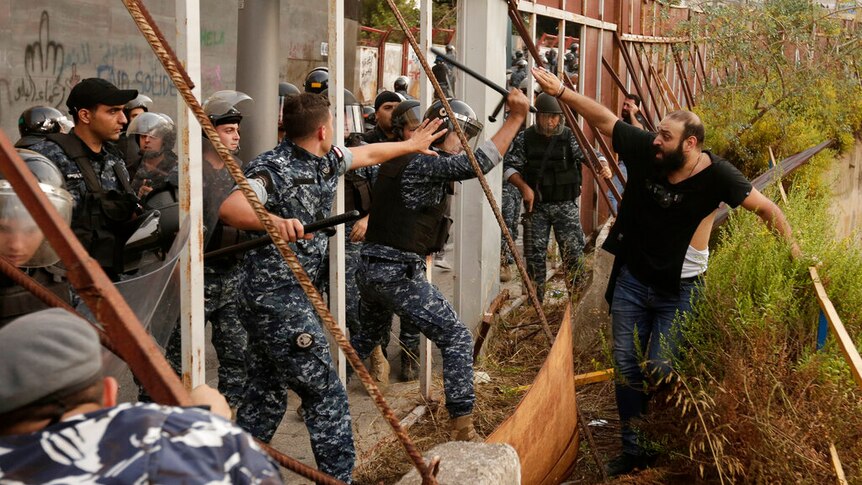 Riot police seen attacking a man on the side of the fence in Lebanon.