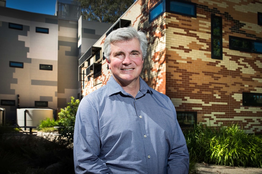 A man stands in front of a a university building.