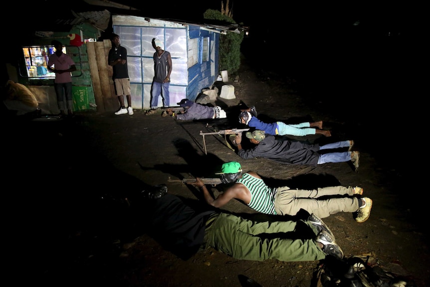 Armed vigilantes lay on the ground with their rifles in Burundi.