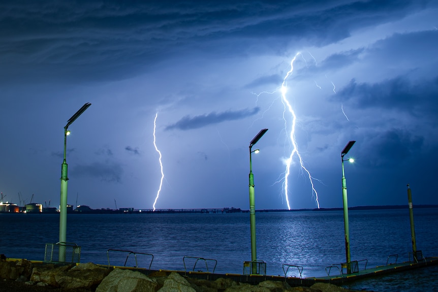Two lightning bolts come down over the water. 