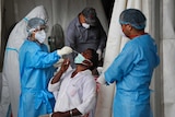 Health workers conduct COVID-19 antigen tests for a male patient in New Delhi, India