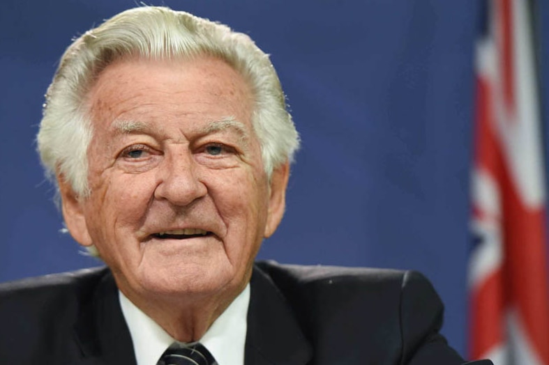 Bob Hawke sits by the Australian flag.