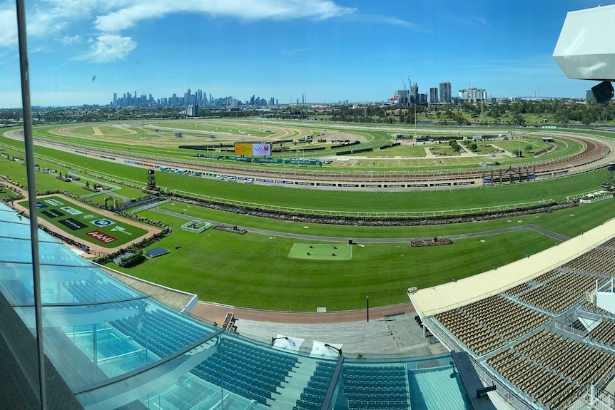 An empty horse racing track with Melbourne's sky line seen behind.