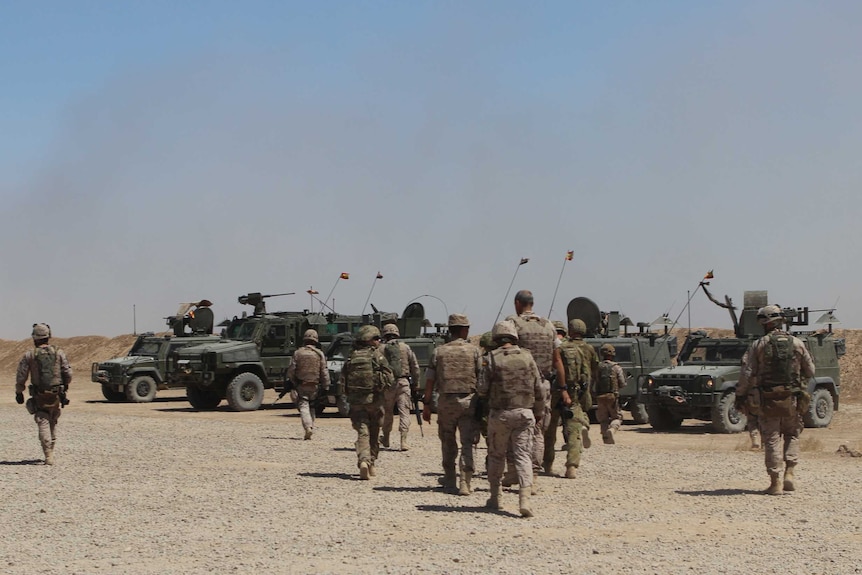 Soldiers walk towards waiting vehicles.