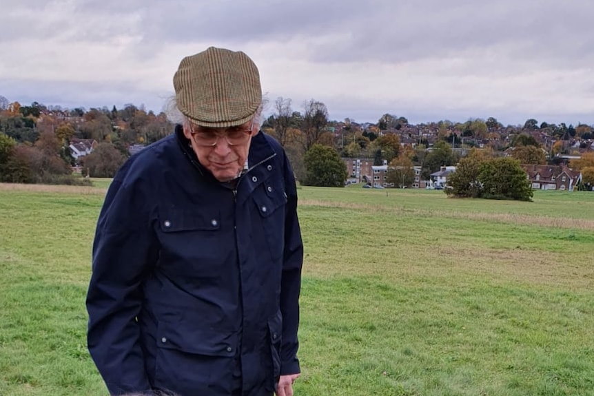 An elderly man with his two young grandchildren playing in the park.