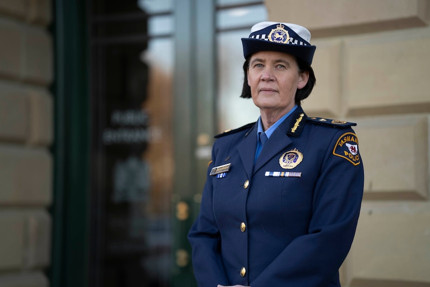 A woman wearing a blue police commissioner's uniform looks seriously at the camera. 