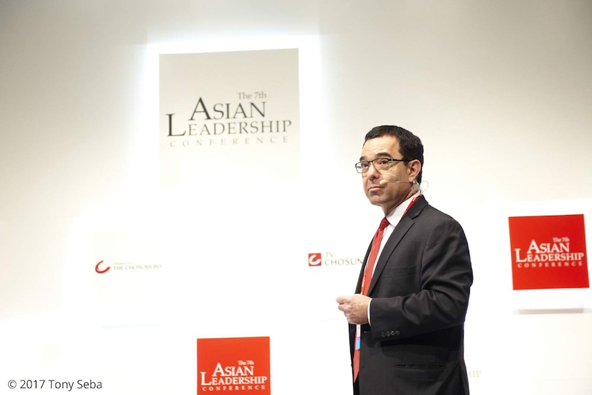 Entrepreneur Tony Seba stands in front of a white wall.