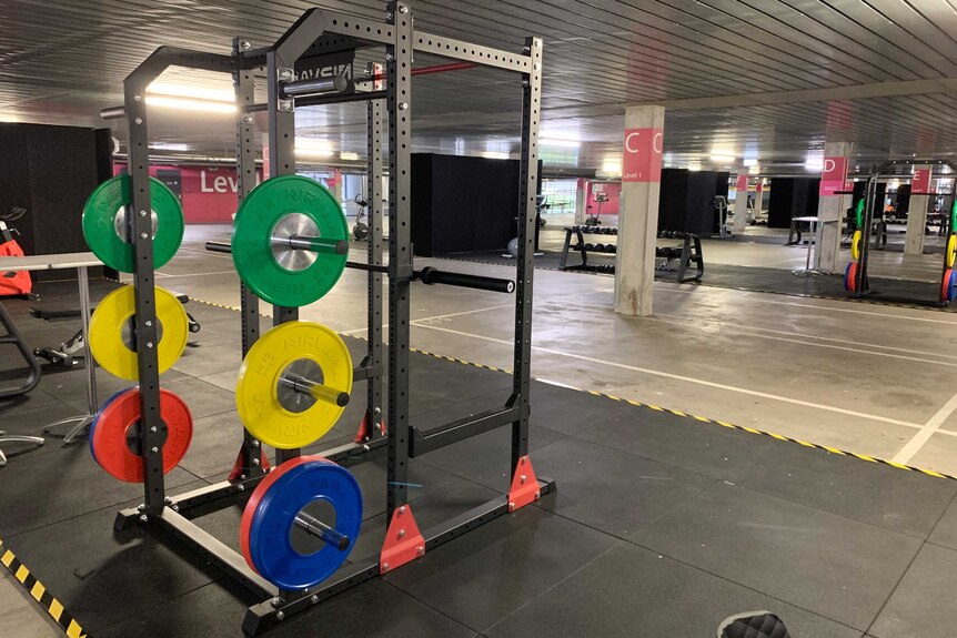 Colourful weights on a squat cage in an underground car park.