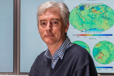 Scientist sits in front of computer screens of earth