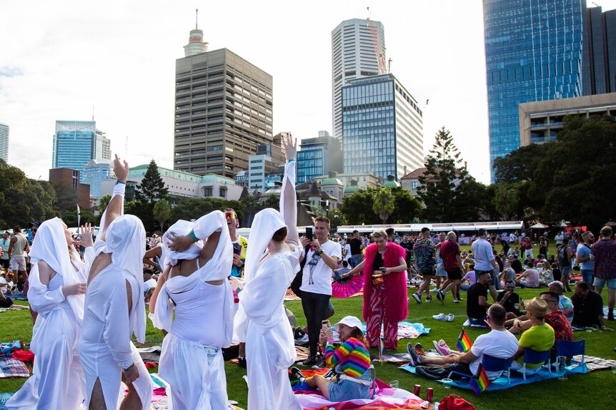 A group dressed in white garb pose for photographs in a city park