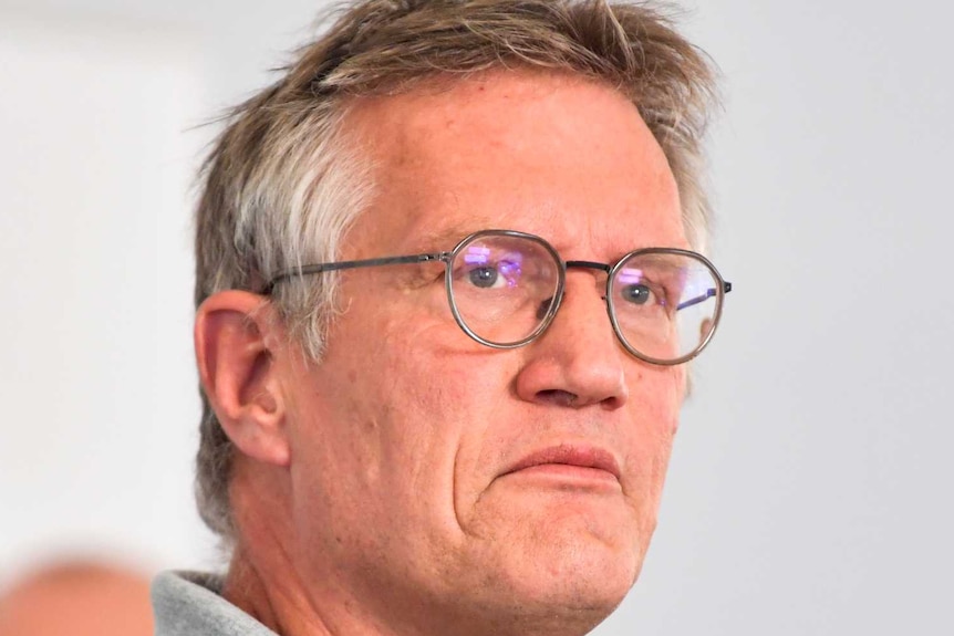 Anders Tegnell, wearing a grey collared shirt and dark-rimmed glasses, frowns slightly