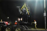 Workers load the monument onto a truck's trailer.
