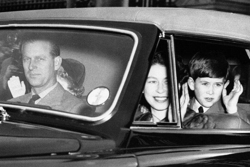 The Duke of Edinburgh keeps both hands on the wheel as Queen Elizabeth II and Prince Charles greet viewers