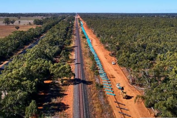 A drone image of a pipe being replaced in the middle of red dirt landscape