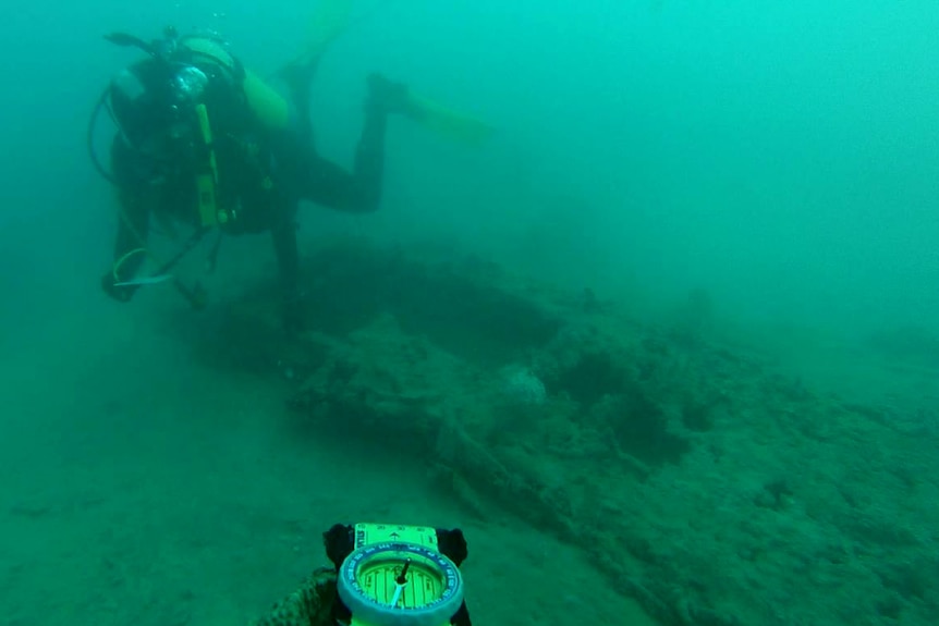 Divers check out the tail of the plane found in waters off Broome