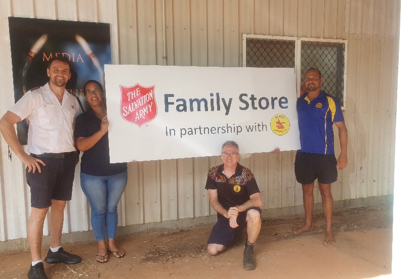 Salvation Army employees hold a sign reading 'Family Store' in front of the Salvation Army store