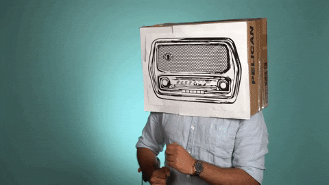 A man dances while wearing a box on his head, which has an image of a radio on it.