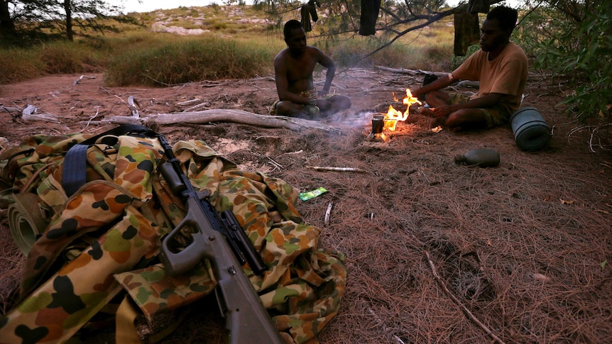 Two indigenous soldiers from NORFORCE sit around a fire on Wigram Island.
