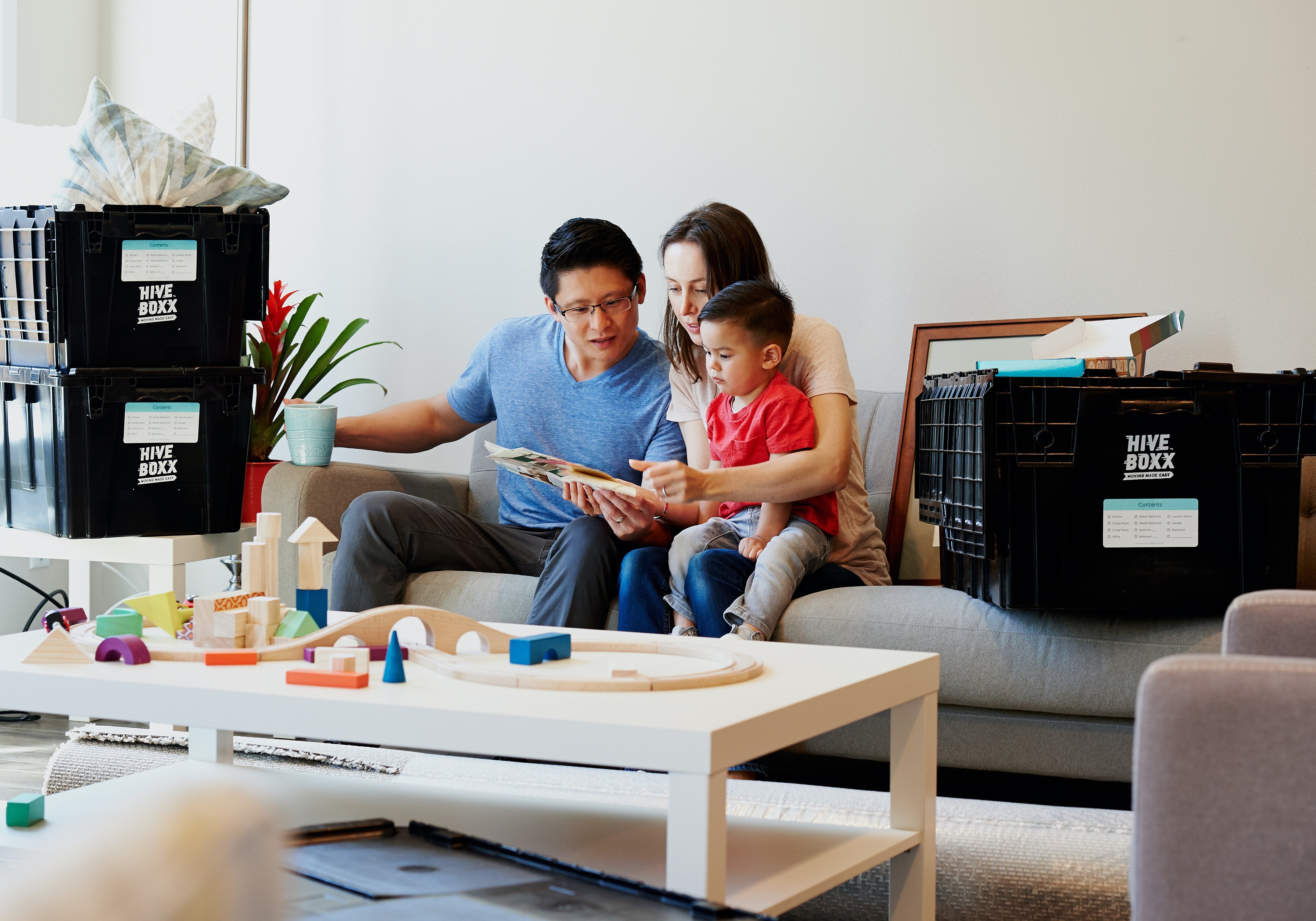 Family of three sitting on the couch in new rental home, in a story about how to find long-term rentals.