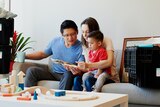 Family of three sitting on the couch in new rental home, in a story about how to find long-term rentals.