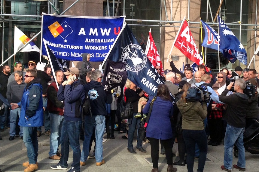 Protestors lined-up outside the Fair Work Commission in Perth waving union banners.