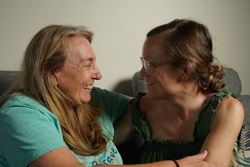 Older woman and younger woman embracing and smiling. 