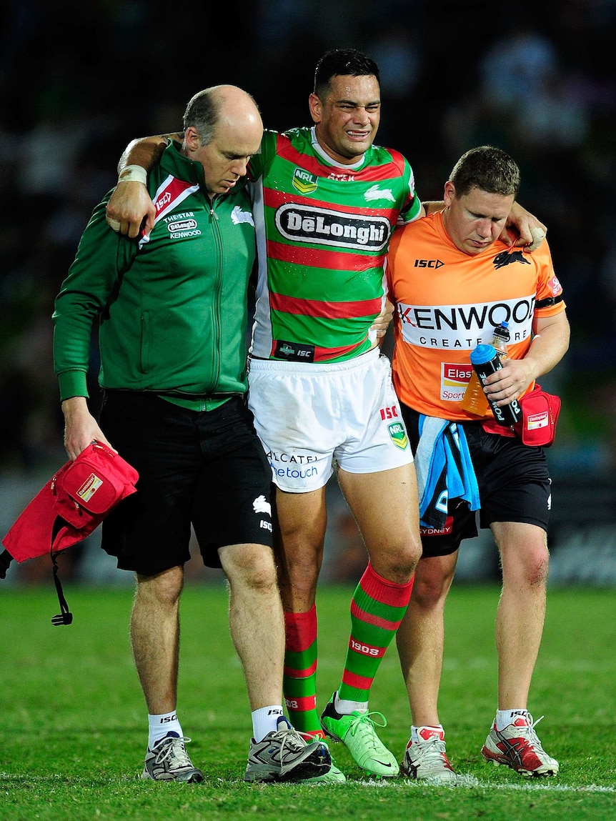 John Sutton of the Rabbitohs is assisted from the field