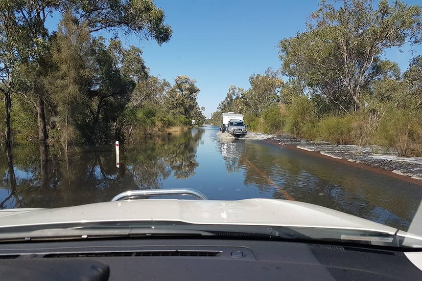 A car drives through a flooded road, picture taken from the dashcam of another car.