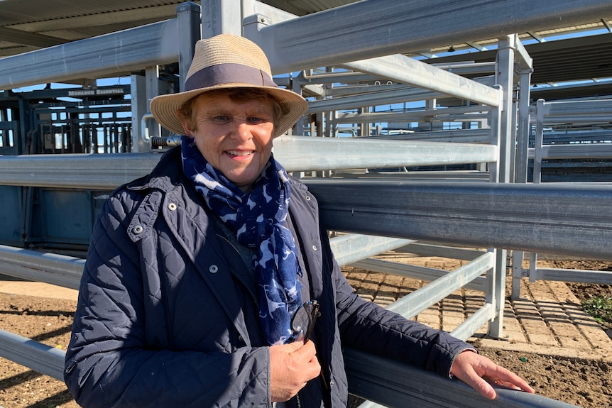 A woman in a blue jacket stands beside a steel rail