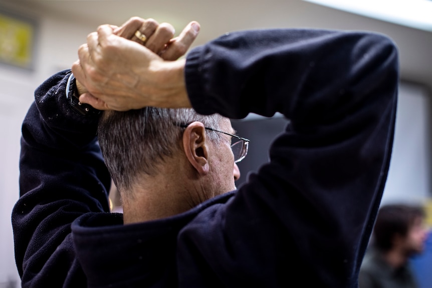 The back of Steve Marton, with both hands on his head, during the meeting.